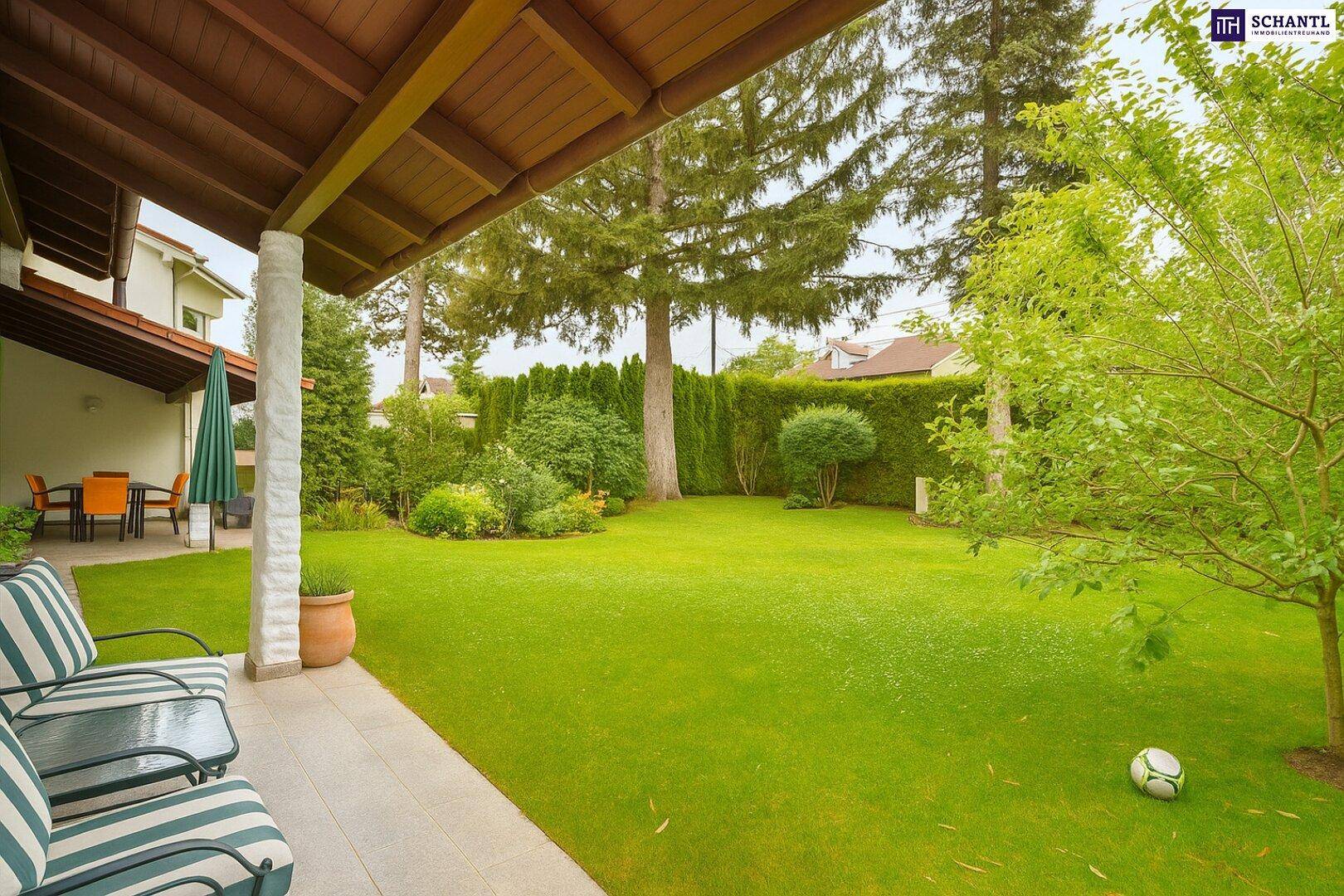 Großer, gepflegter Garten mit weitläufiger Rasenfläche, hohen Bäumen und einer überdachten Terrasse.