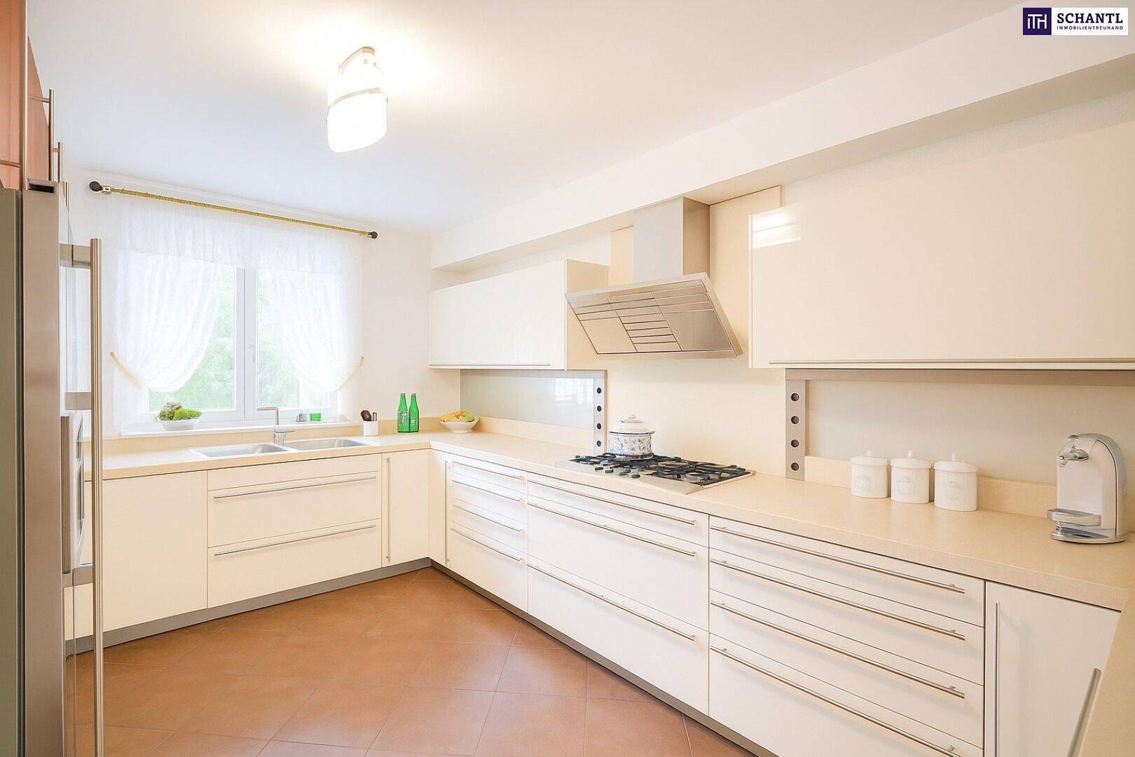 Moderne Küche mit hellen Schränken, integrierten Geräten und einem Fenster, das für natürliches Licht sorgt.