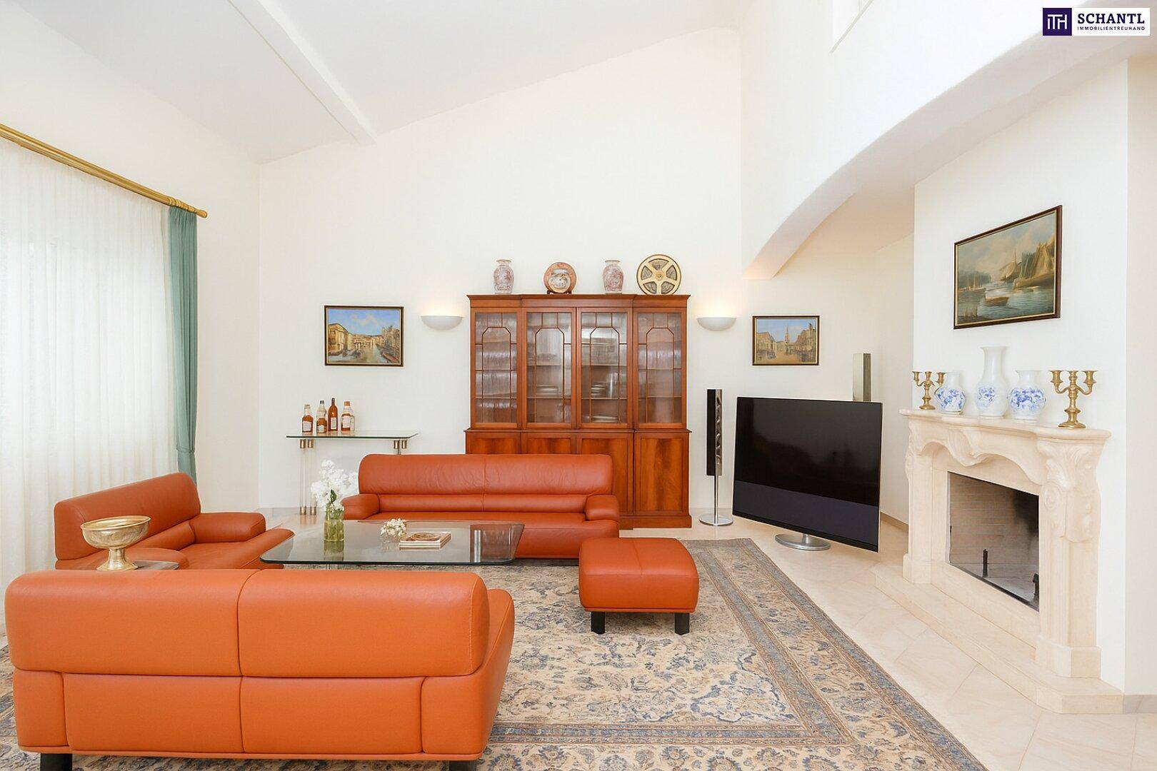 Helles Wohnzimmer mit bequemen orangefarbenen Ledersofas, einem Kamin und einem großen Fernseher.