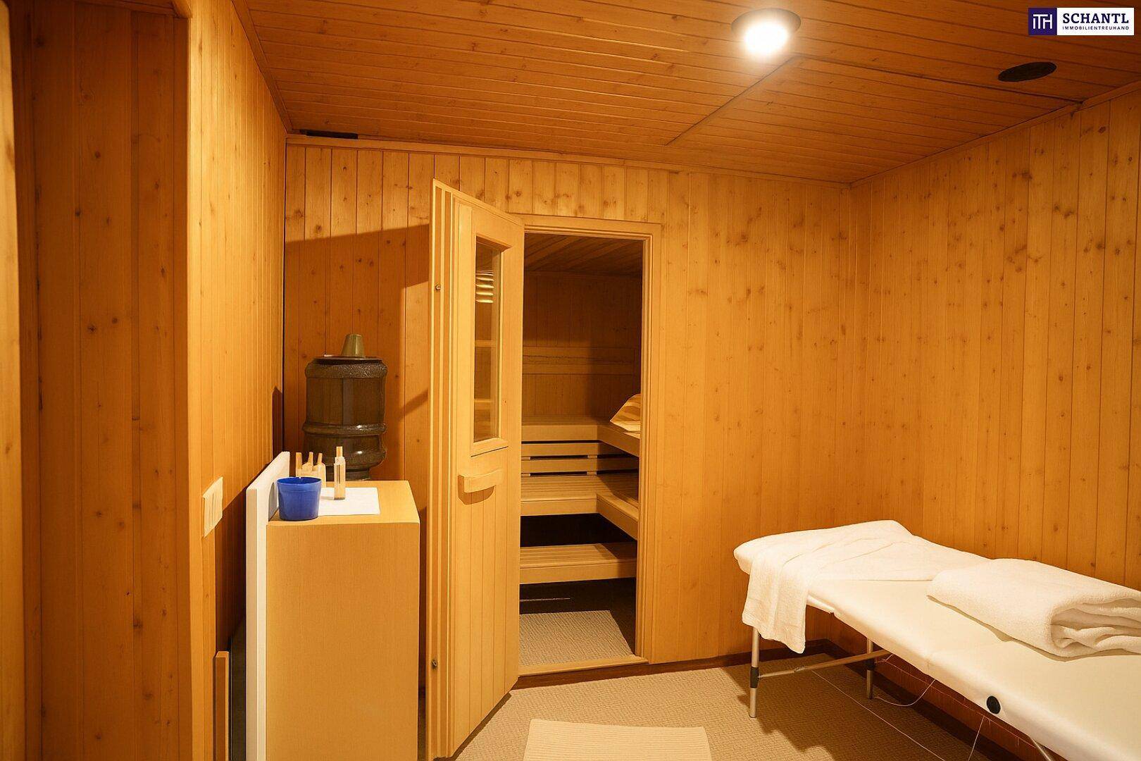 Geräumiger Wellnessbereich mit einer holzvertäfelten Sauna und einer Liege zum Entspannen.