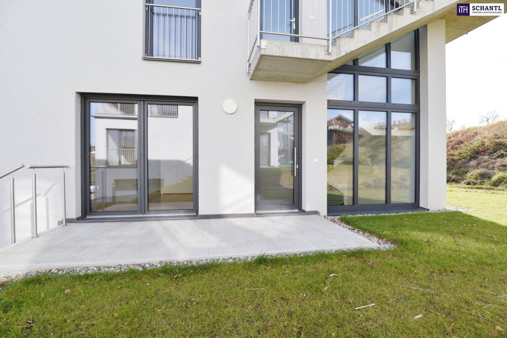 Ebenerdige Terrasse mit Zugang zum Garten und großen Fenstern der modernen Fassade des Neubaus.