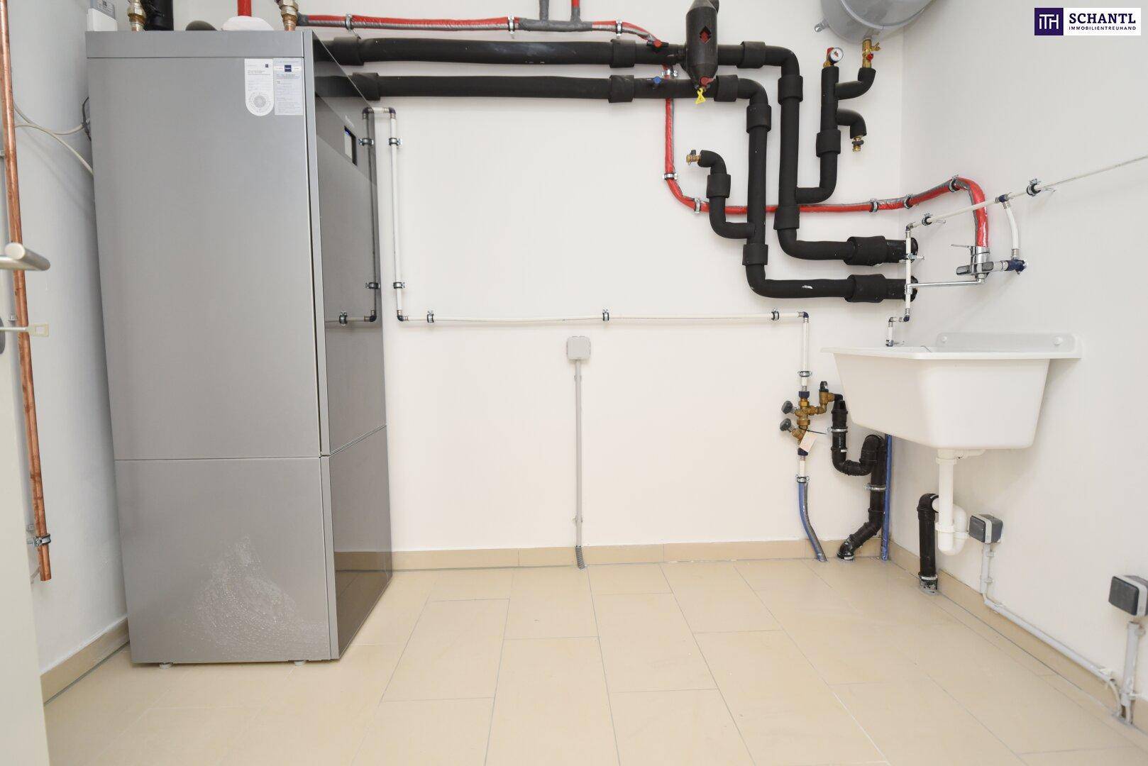 Technikraum mit Heizungsanlage, Waschbecken und sichtbaren Rohrleitungen für die Versorgung.