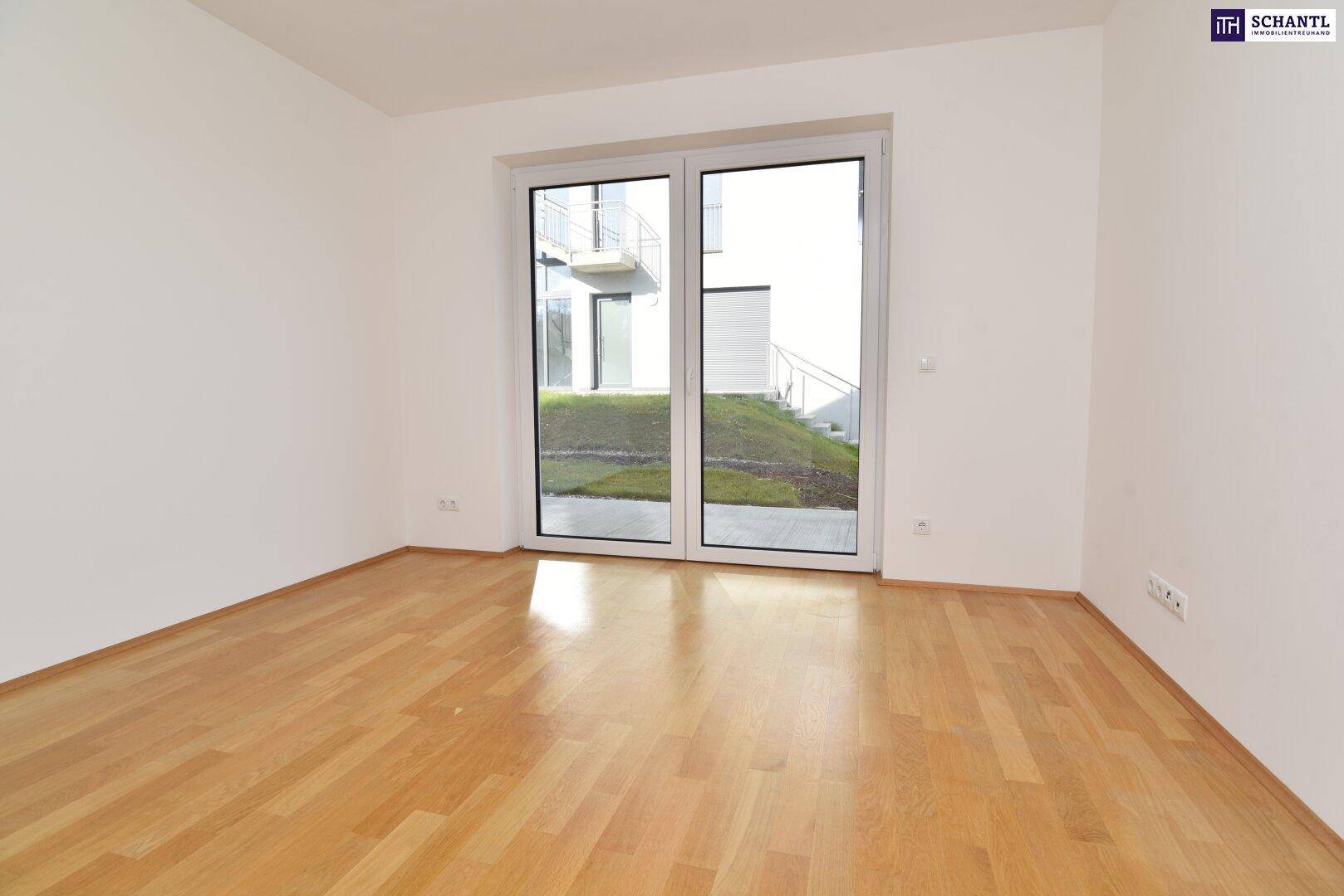 Helles, leeres Zimmer mit Parkettboden und Zugang zu einer ebenerdigen Terrasse oder Garten.