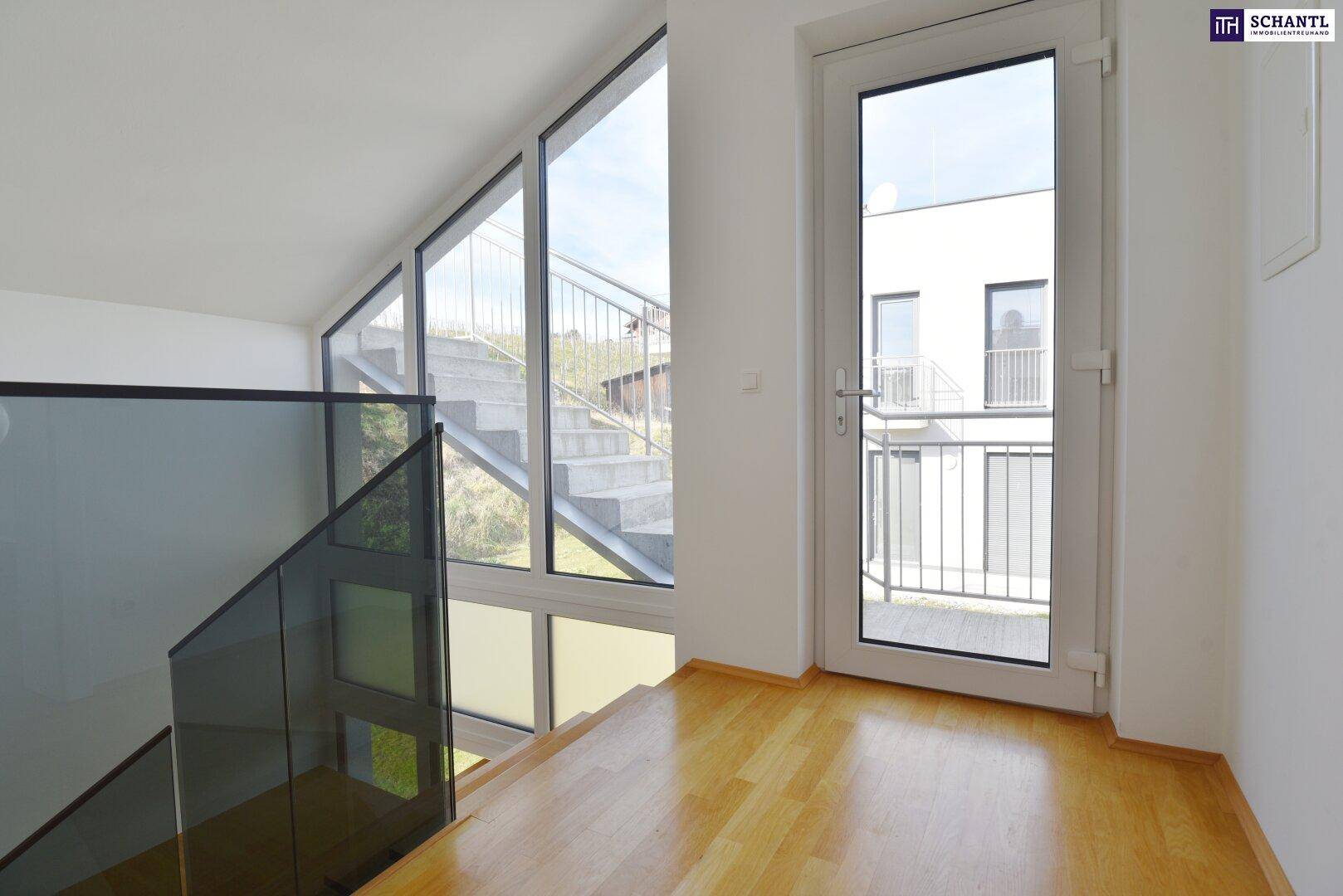 Heller Treppenaufgang mit Glasgeländer und großer Fensterfront, die den Außenbereich zeigt.
