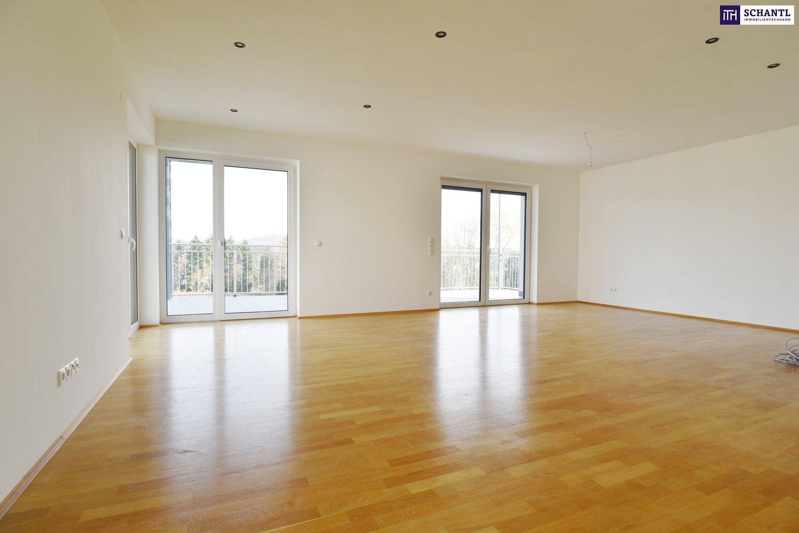 Helles, leeres Wohnzimmer mit Parkettboden und Zugang zu zwei Balkonen, bietet viel natürliches Licht.