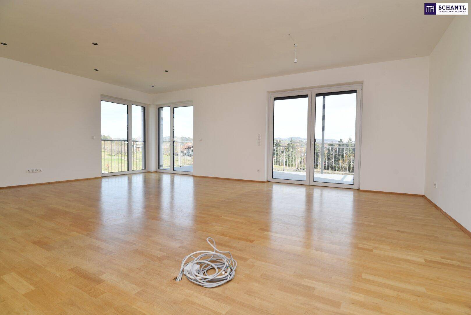 Großzügiges Wohnzimmer mit Parkettboden und mehreren Fenstertüren, die einen weiten Blick bieten.