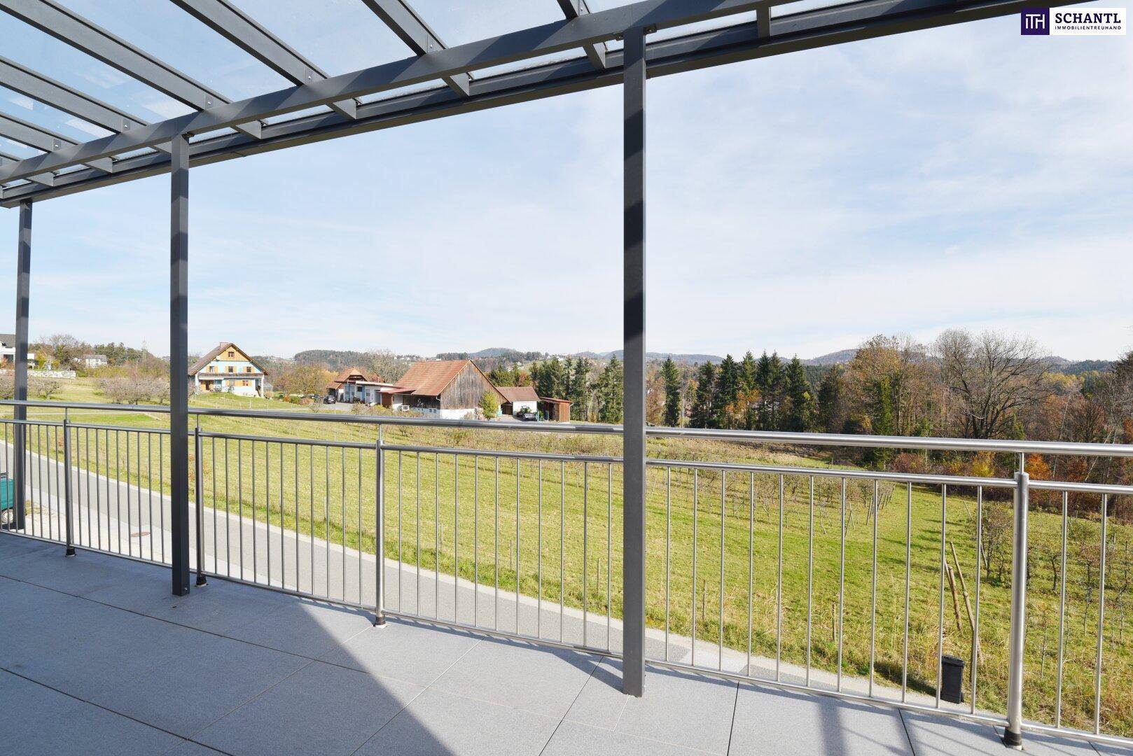 Überdachte Terrasse mit Fliesenboden und weitem Blick über die grüne Landschaft.