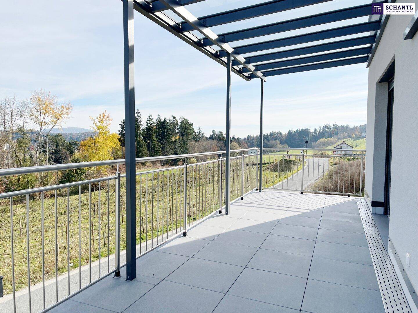 Große, geflieste Terrasse mit Überdachung und weitem Blick auf die umliegende Natur.