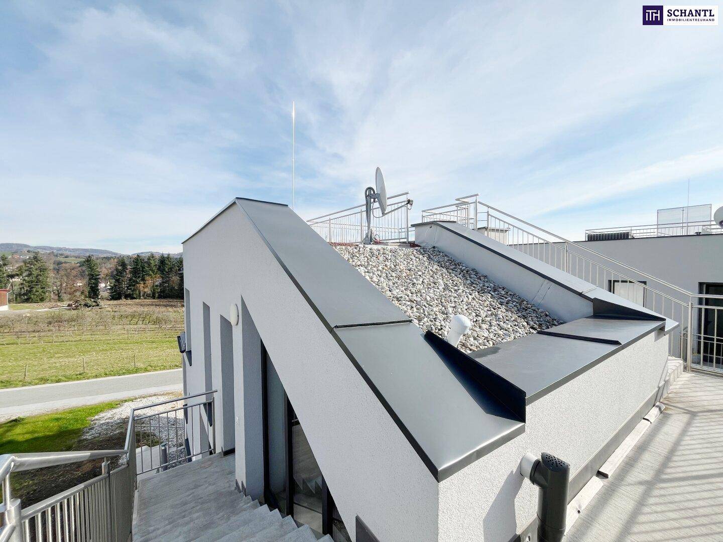 Dachterrasse mit Kiesbelag und weitem Blick über die hügelige Landschaft und Gebäude.