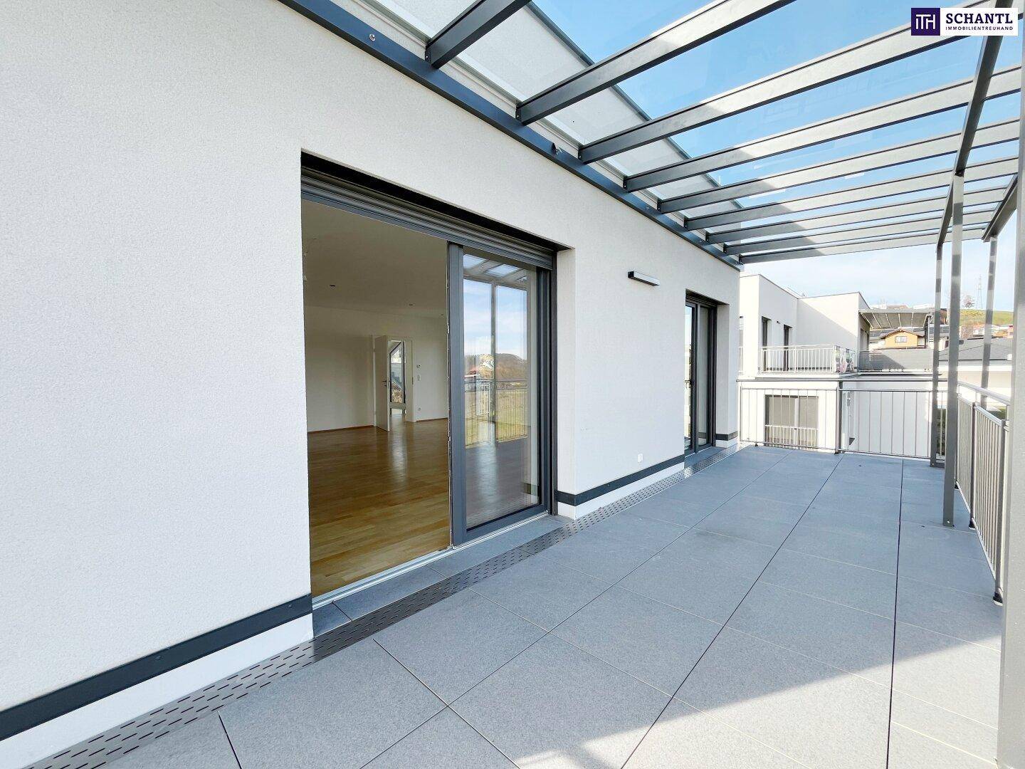 Überdachte Terrasse mit Schiebetüren und Blick in den hellen Innenraum des Hauses.