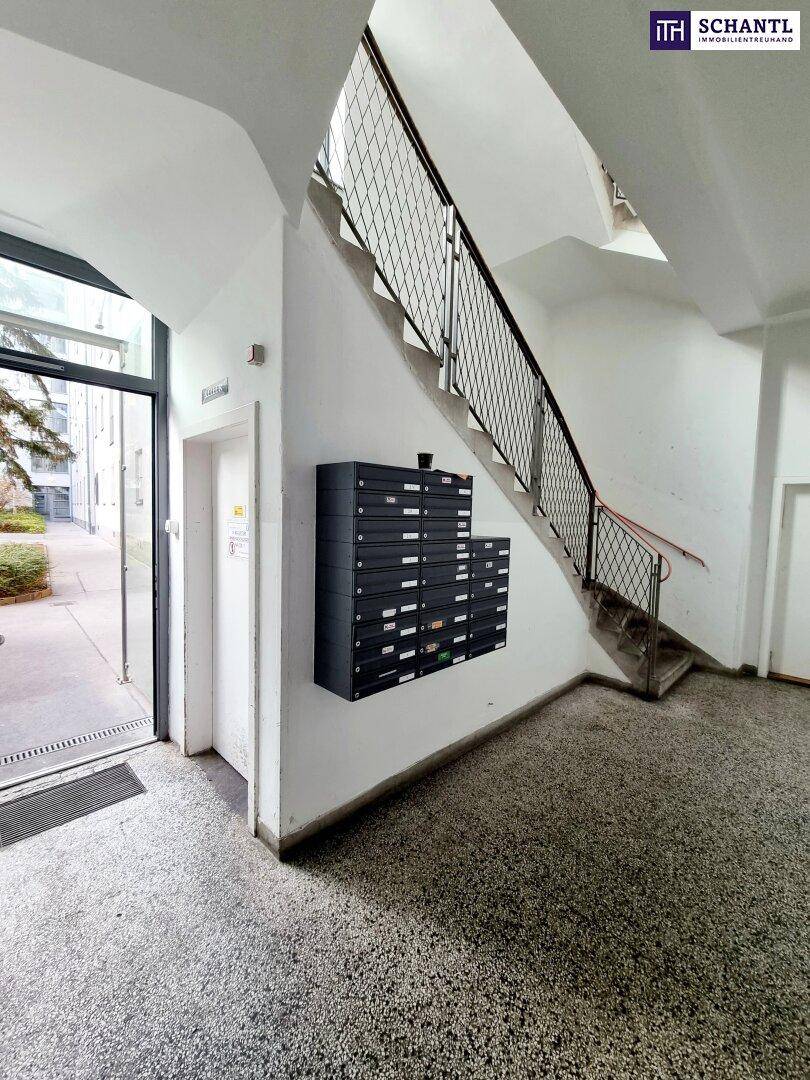 Eingangsbereich eines Mehrfamilienhauses mit Briefkästen und Treppenaufgang.