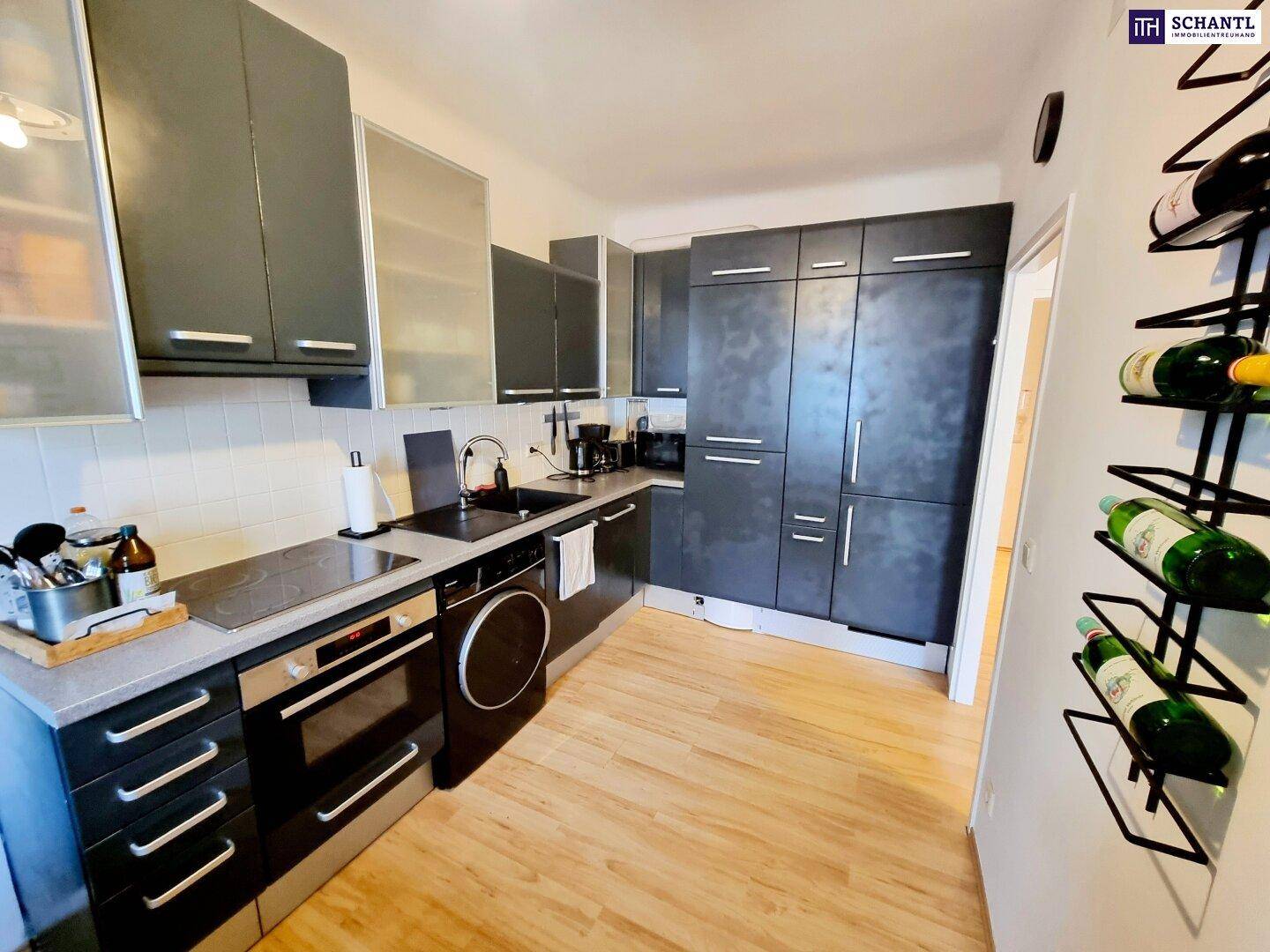 Moderne Küche mit dunklen Schränken, integrierten Geräten und Holzboden.