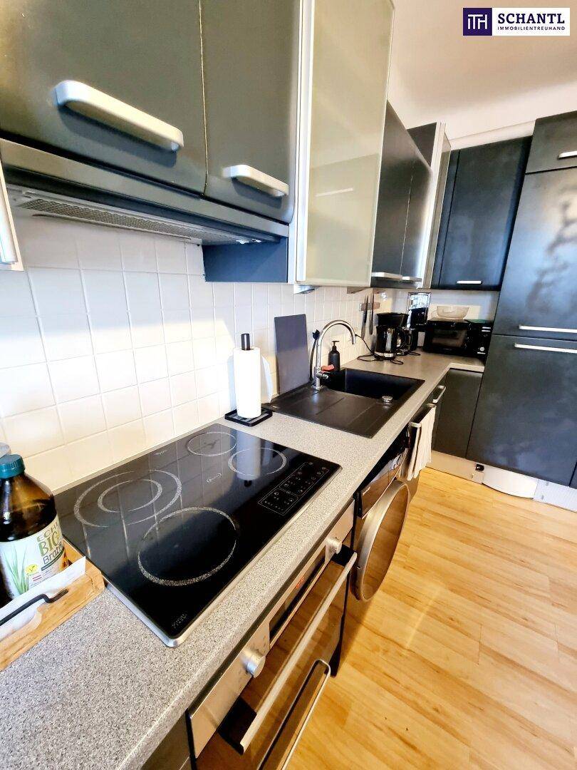 Moderne Küche mit dunklen Schränken, Induktionskochfeld und integrierten Geräten.