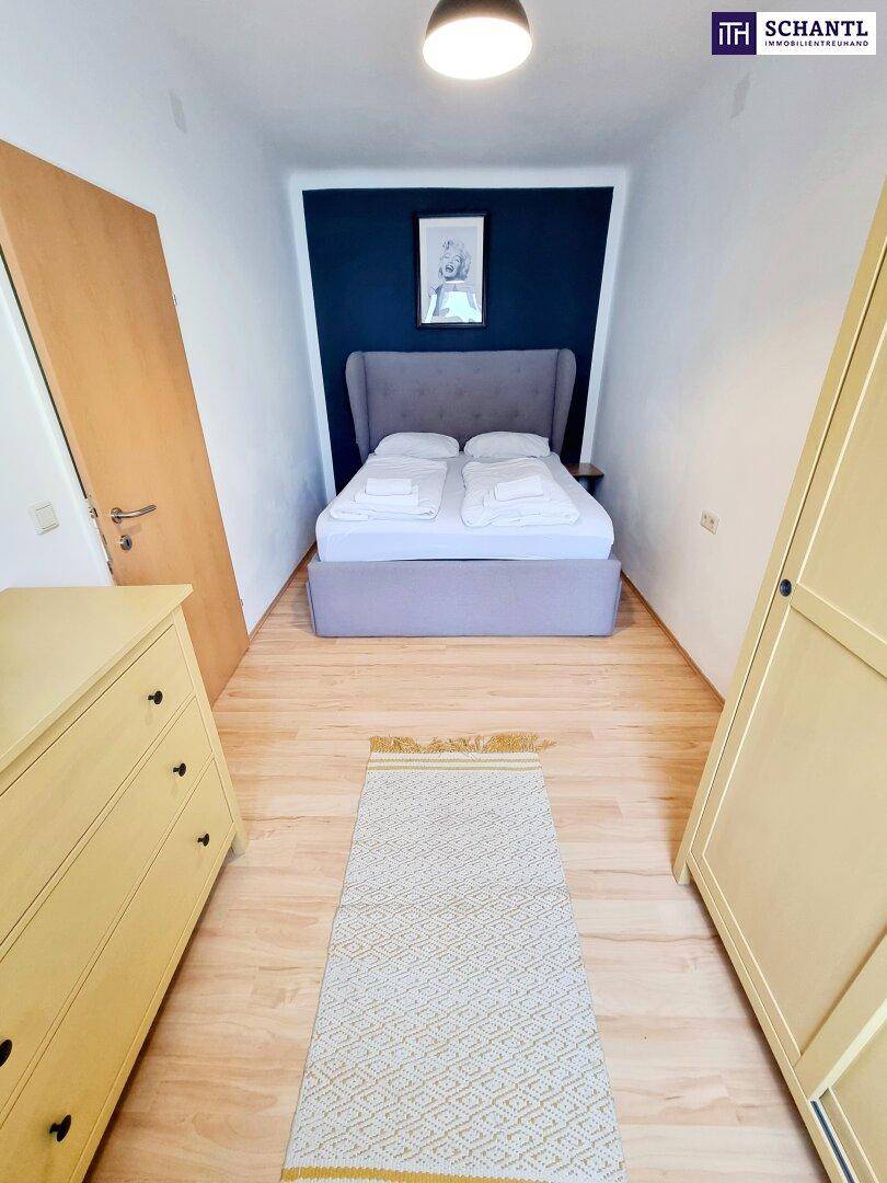Kleines Schlafzimmer mit Doppelbett, Holzboden und dunkelblauer Akzentwand.