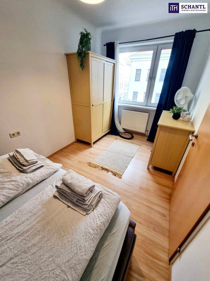 Schlafzimmer mit Doppelbett, hellem Holzschrank und Fenster mit Blick nach draußen.