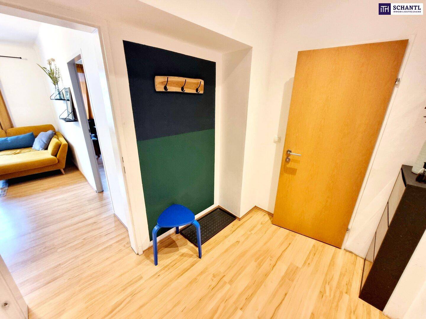 Eingangsbereich mit Holzboden, Garderobe und Blick in den Wohnbereich.