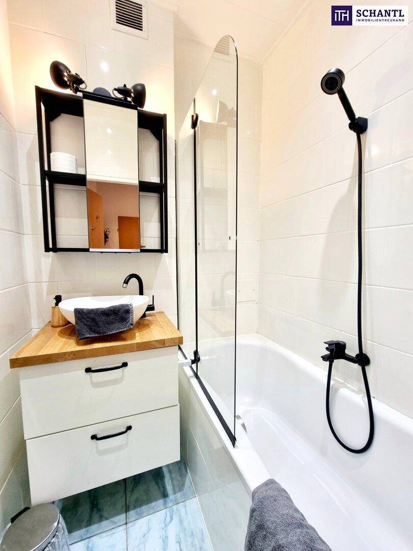 Modernes Badezimmer mit Badewanne, Duschwand, Holzwaschtisch und weißen Fliesen.