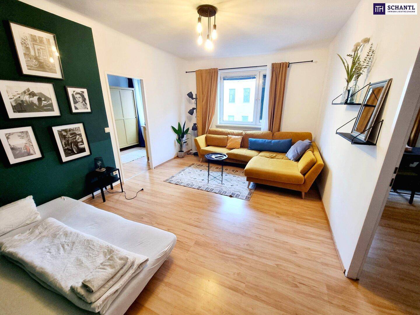 Helles Wohnzimmer mit gelbem Ecksofa, Holzboden und einer dunkelgrünen Akzentwand.