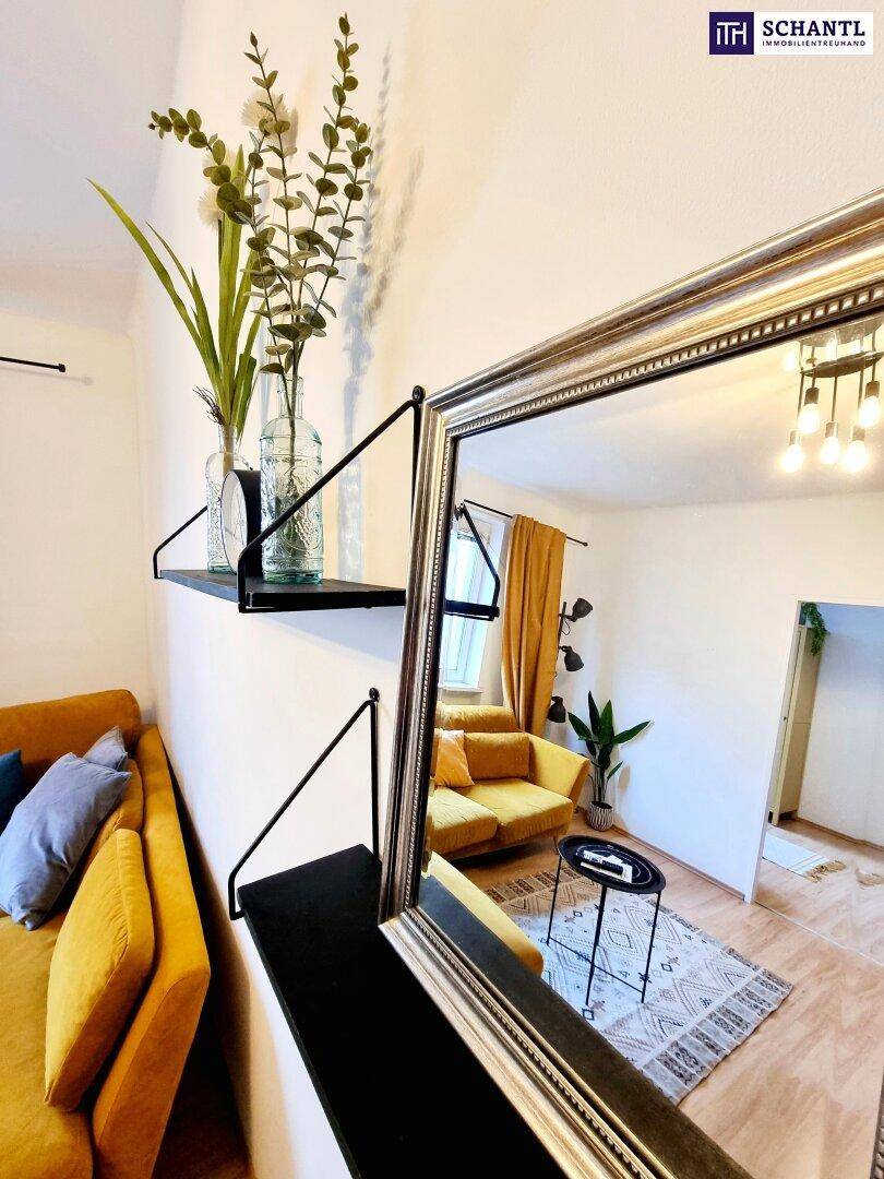 Wohnzimmer mit gelbem Sofa, Holzboden und großem Spiegel, der den Raum reflektiert.