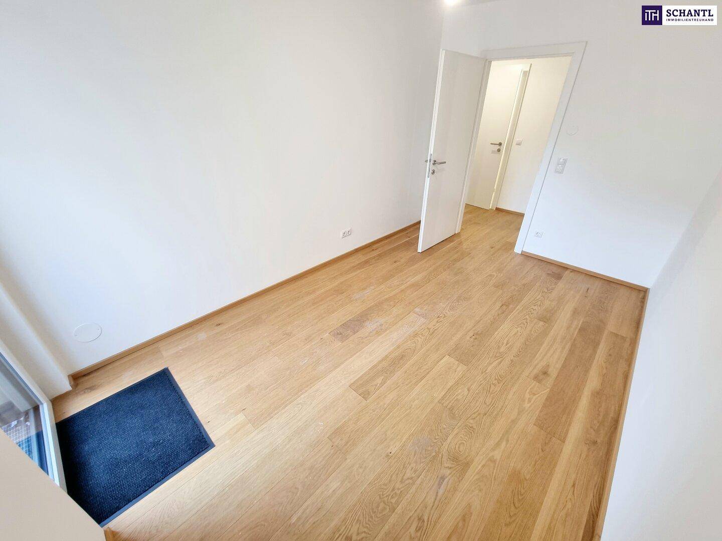 Helles Schlafzimmer mit Parkettboden und weiß gestrichenen Wänden.