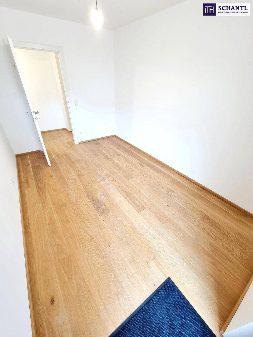 Helles Schlafzimmer mit Parkettboden und weiß gestrichenen Wänden.