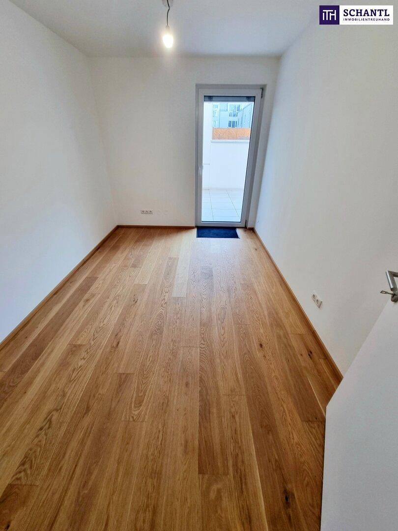 Helles Schlafzimmer mit Parkettboden und Zugang zu einem Außenbereich.