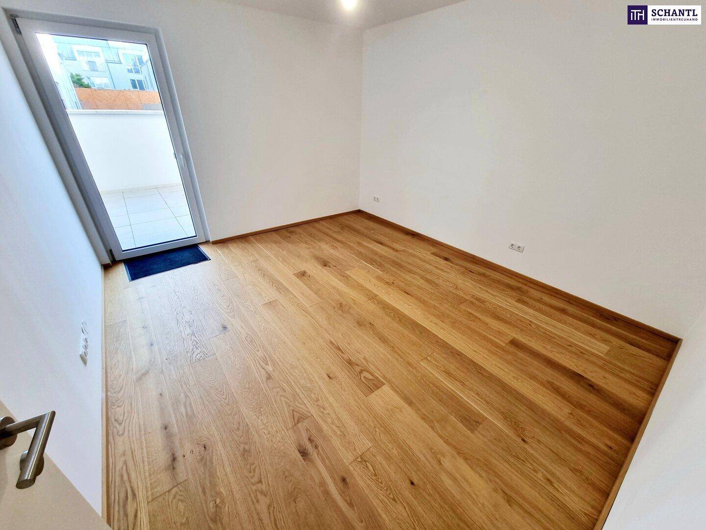 Helles Schlafzimmer mit Parkettboden und Zugang zu einem Außenbereich.