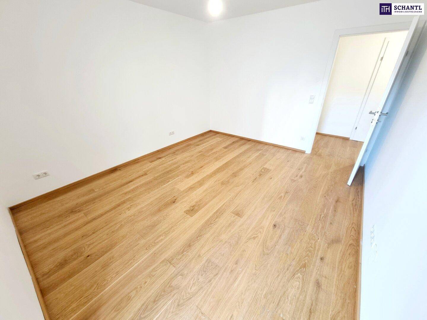 Helles Schlafzimmer mit Parkettboden und weiß gestrichenen Wänden.