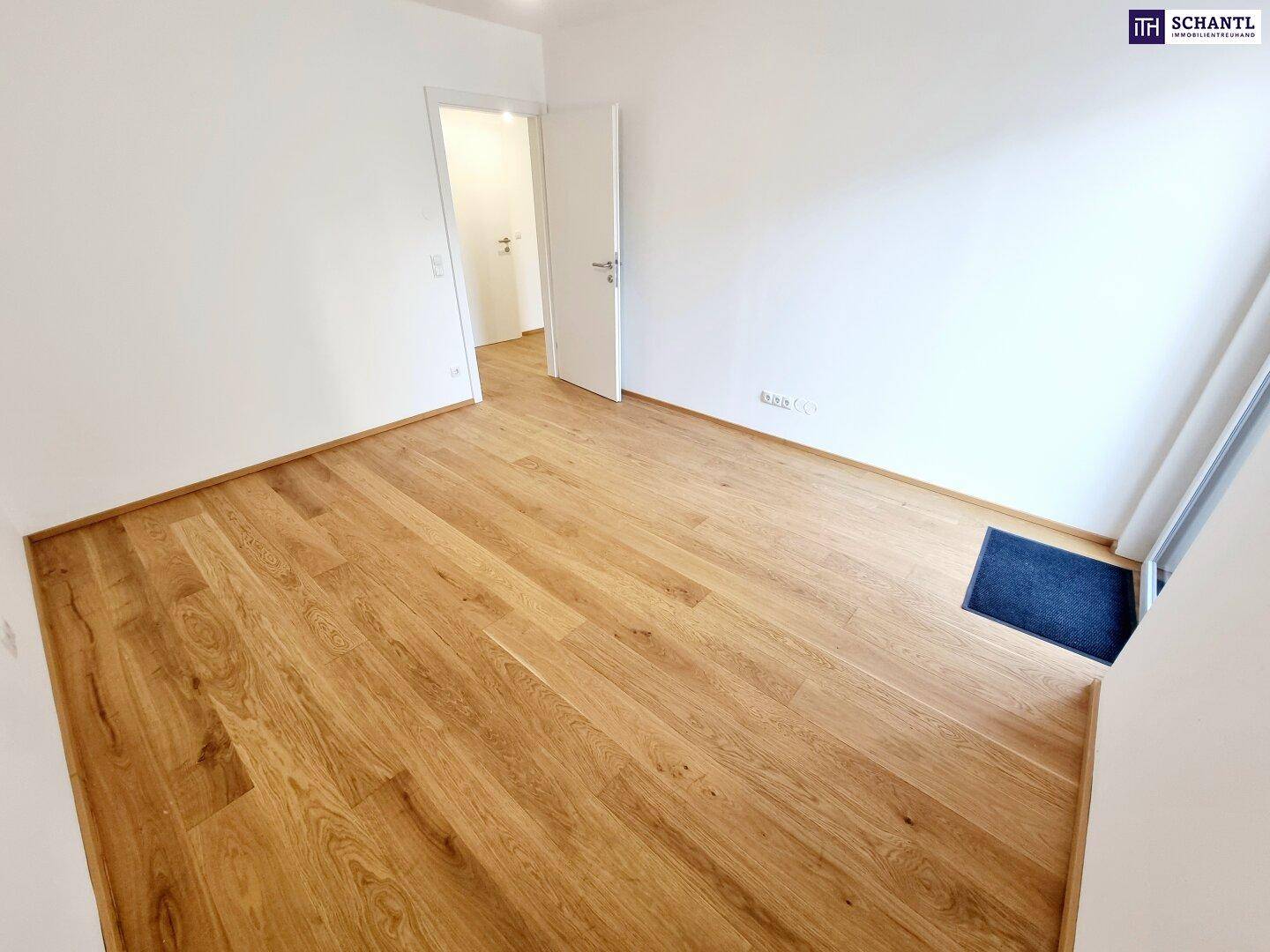 Helles Schlafzimmer mit Parkettboden und weiß gestrichenen Wänden.