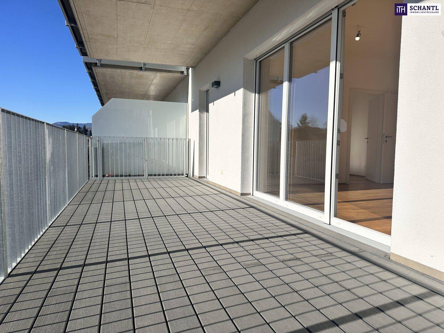 Breiter Balkon mit modernen Fliesen und Zugang zu den Innenräumen, ideal für Entspannung im Freien.