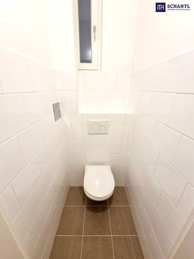 Gäste-WC mit wandhängender Toilette, weißen Fliesen und einem kleinen Fenster für Belüftung.