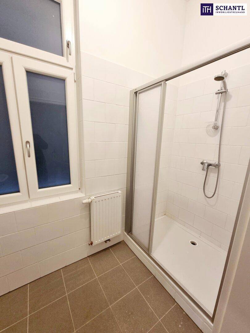 Modernes Badezimmer mit Duschkabine, weißen Wandfliesen und einem Fenster für natürliche Belüftung.