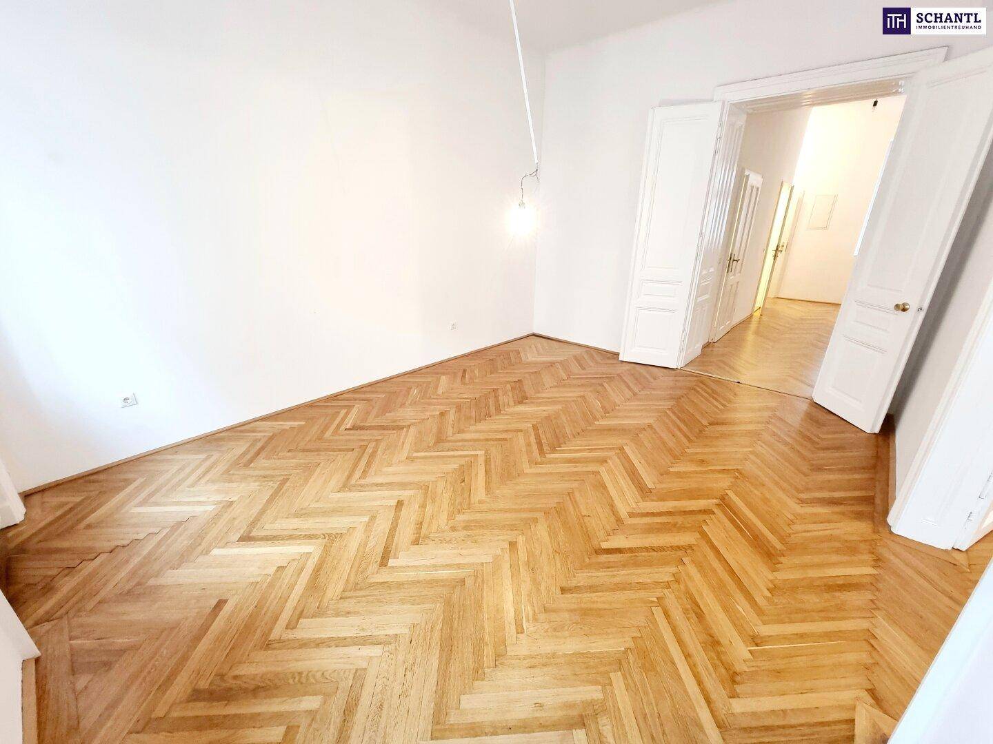 Heller und geräumiger Raum mit Fischgrätparkett und hohen Decken, ideal für ein Wohnzimmer.