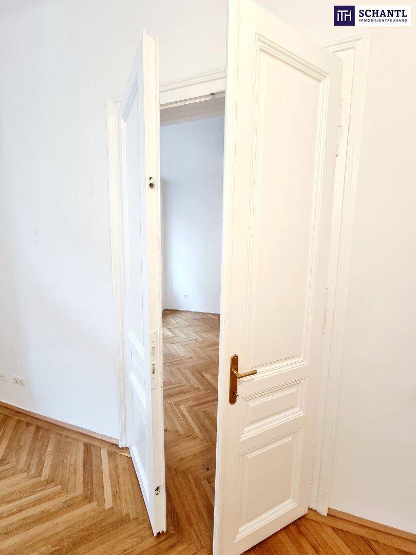 Offene Tür gibt den Blick frei auf einen hellen Raum mit klassischem Fischgrätparkett.
