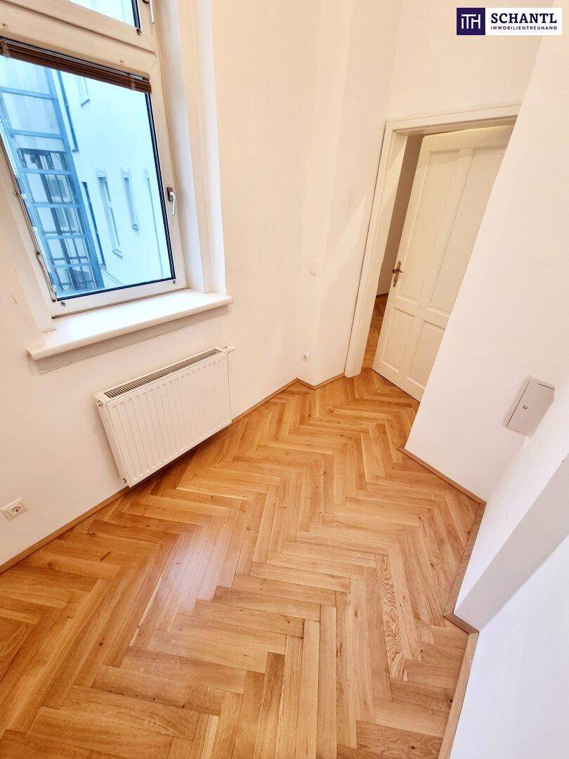 Heller Raum mit Fischgrätparkett und einem großen Fenster, das viel Tageslicht in den Raum bringt.