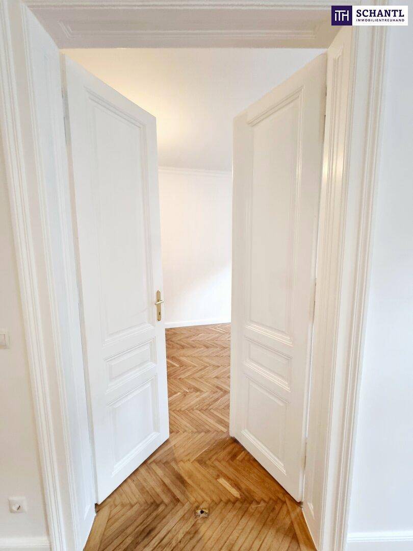 Offene Flügeltüren geben den Blick frei auf ein weiteres Zimmer mit Fischgrätparkett.