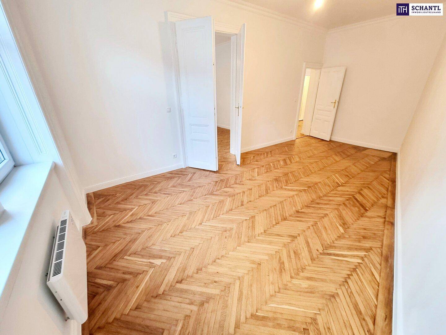 Helles Zimmer mit Fischgrätparkett und weiß gestrichenen Wänden, bereit zur individuellen Gestaltung.