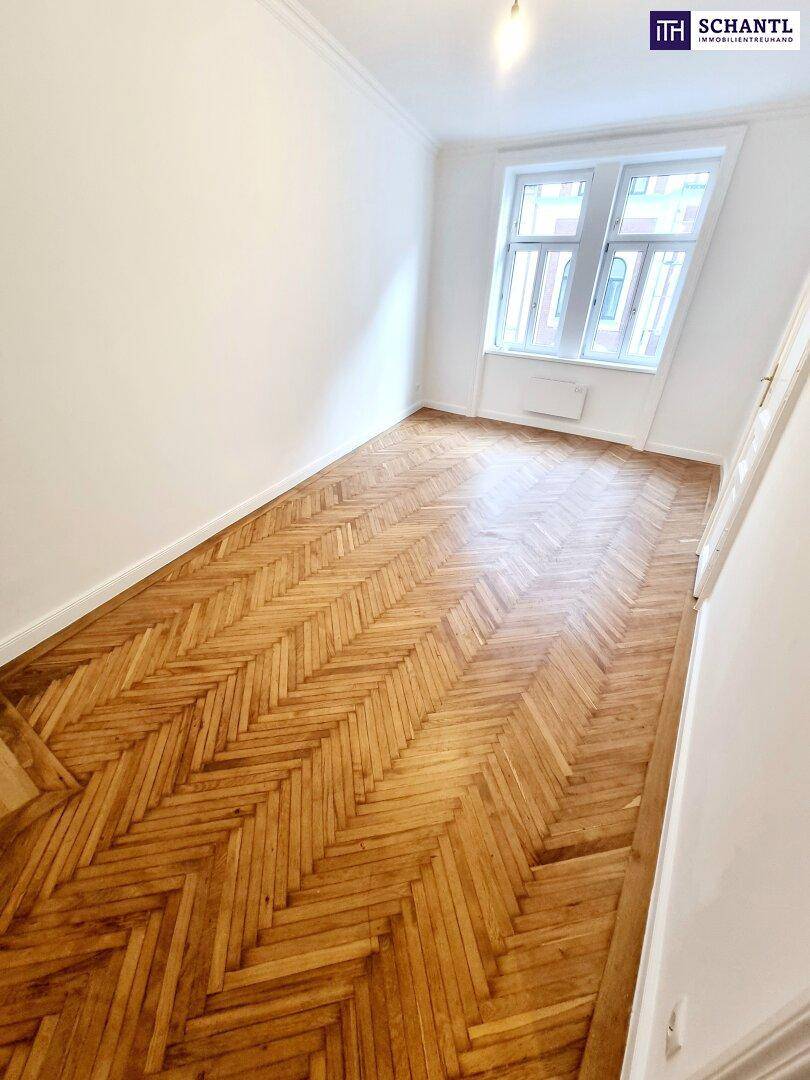 Lichtdurchflutetes Zimmer mit Fischgrätparkett und großen Fenstern, ideal für ein gemütliches Zuhause.