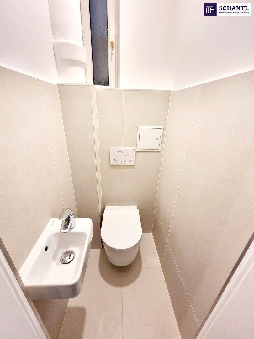 Modernes Gäste-WC mit wandhängender Toilette, kleinem Waschbecken und hellen Fliesen.