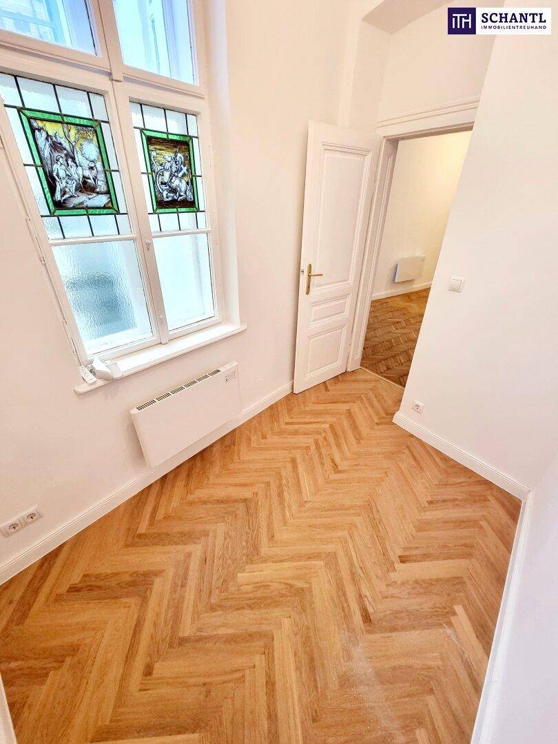 Helles Zimmer mit Fischgrätparkett und einem dekorativen Buntglasfenster, das Charakter verleiht.