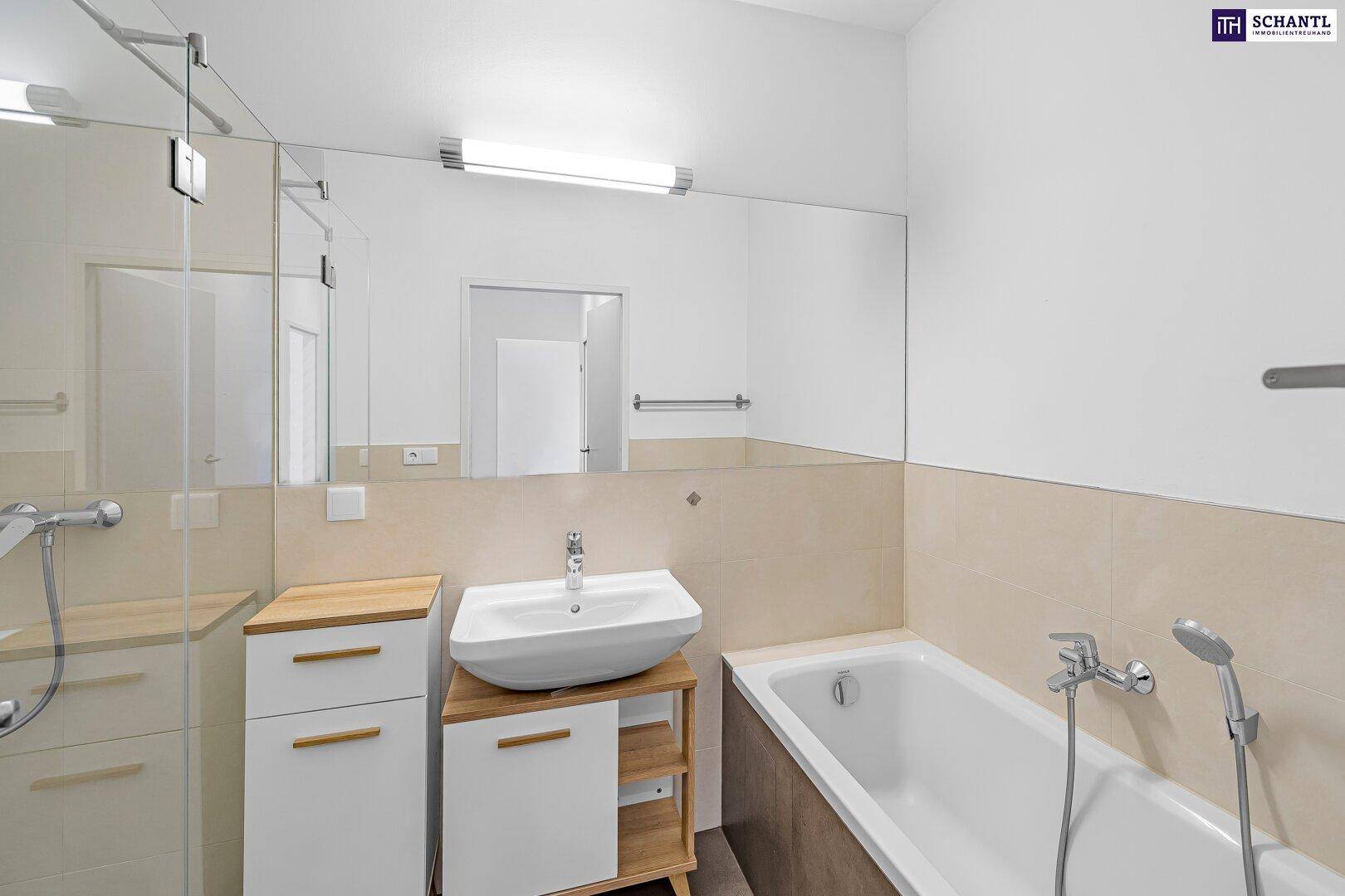 Modernes Badezimmer mit Badewanne, Waschbecken und großem Spiegel, hell gefliest.