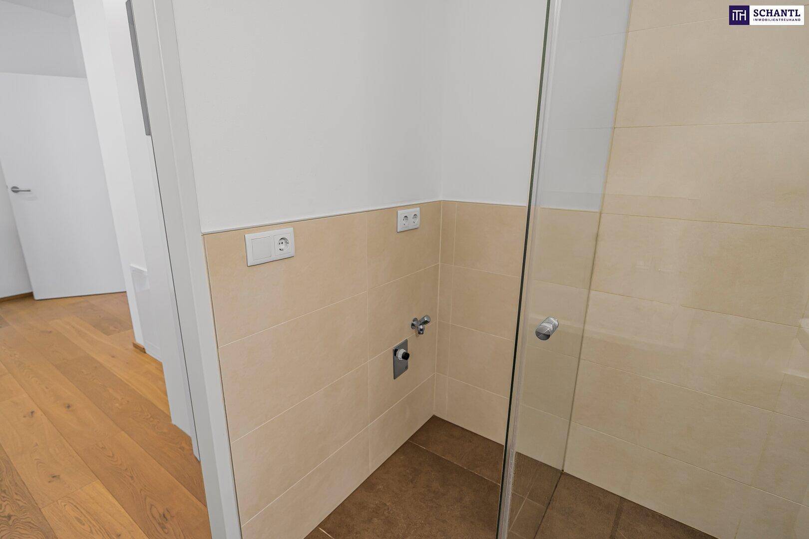 Duschbereich im Badezimmer mit Glasabtrennung und hellen Fliesen, vorbereitet für eine Dusche.