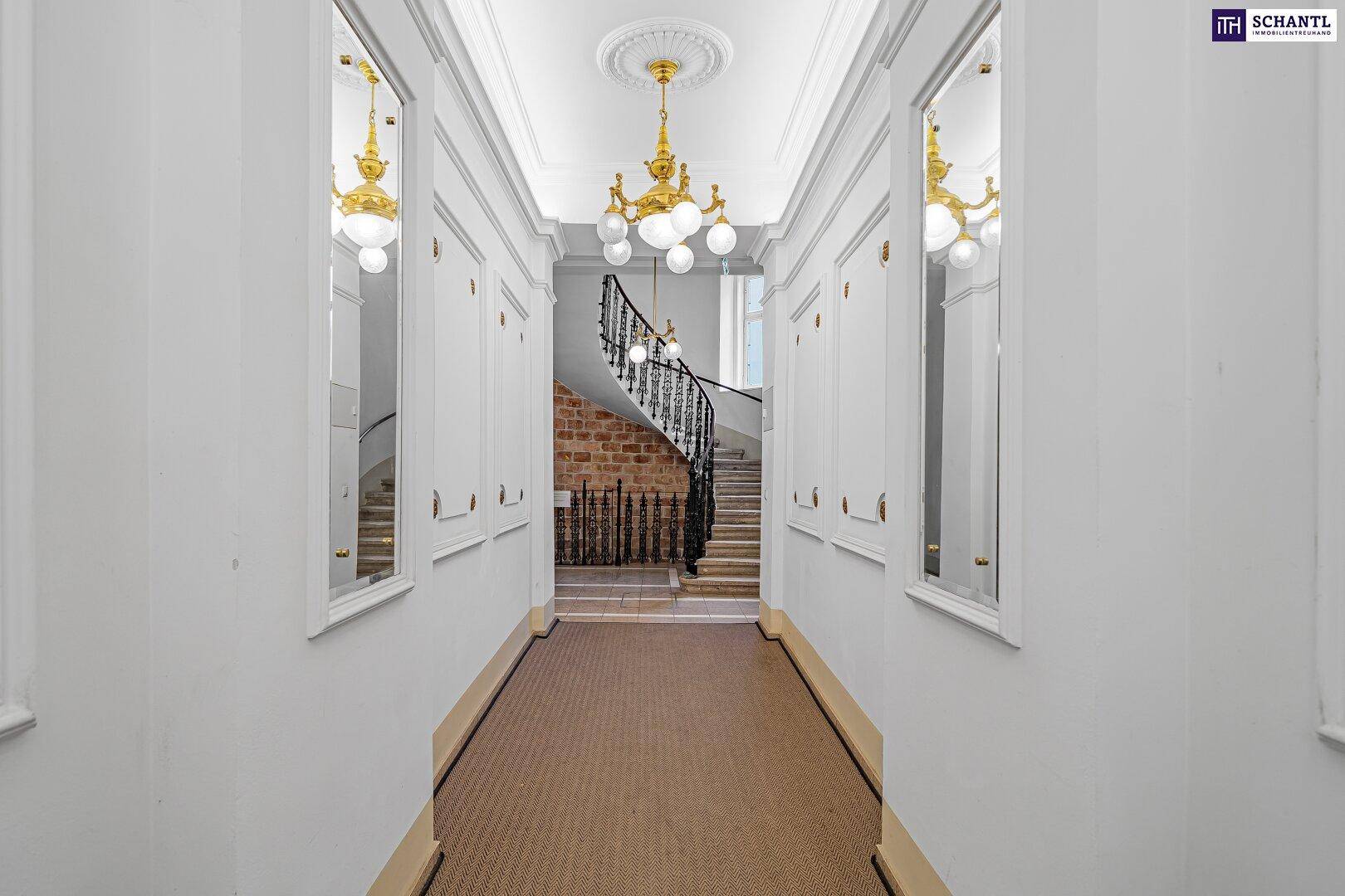 Eleganter Flur mit Stuckdecke, Kronleuchtern und Blick auf eine geschwungene Treppe.