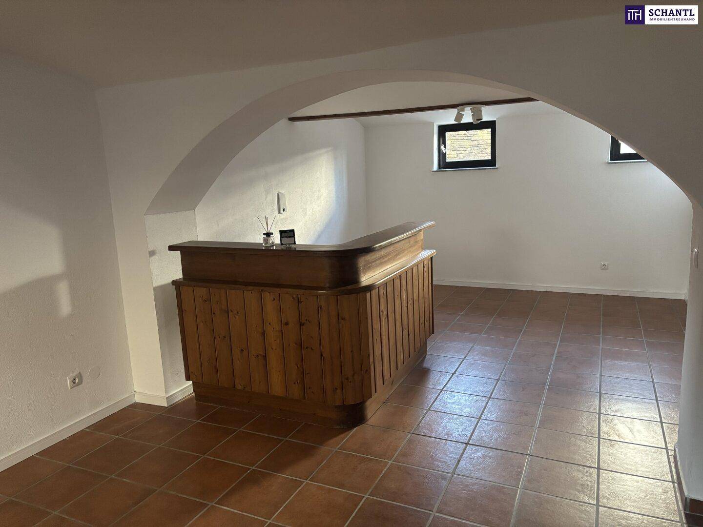 Geräumiger Kellerraum mit gefliestem Boden, Holzbalken und einer rustikalen Bar.