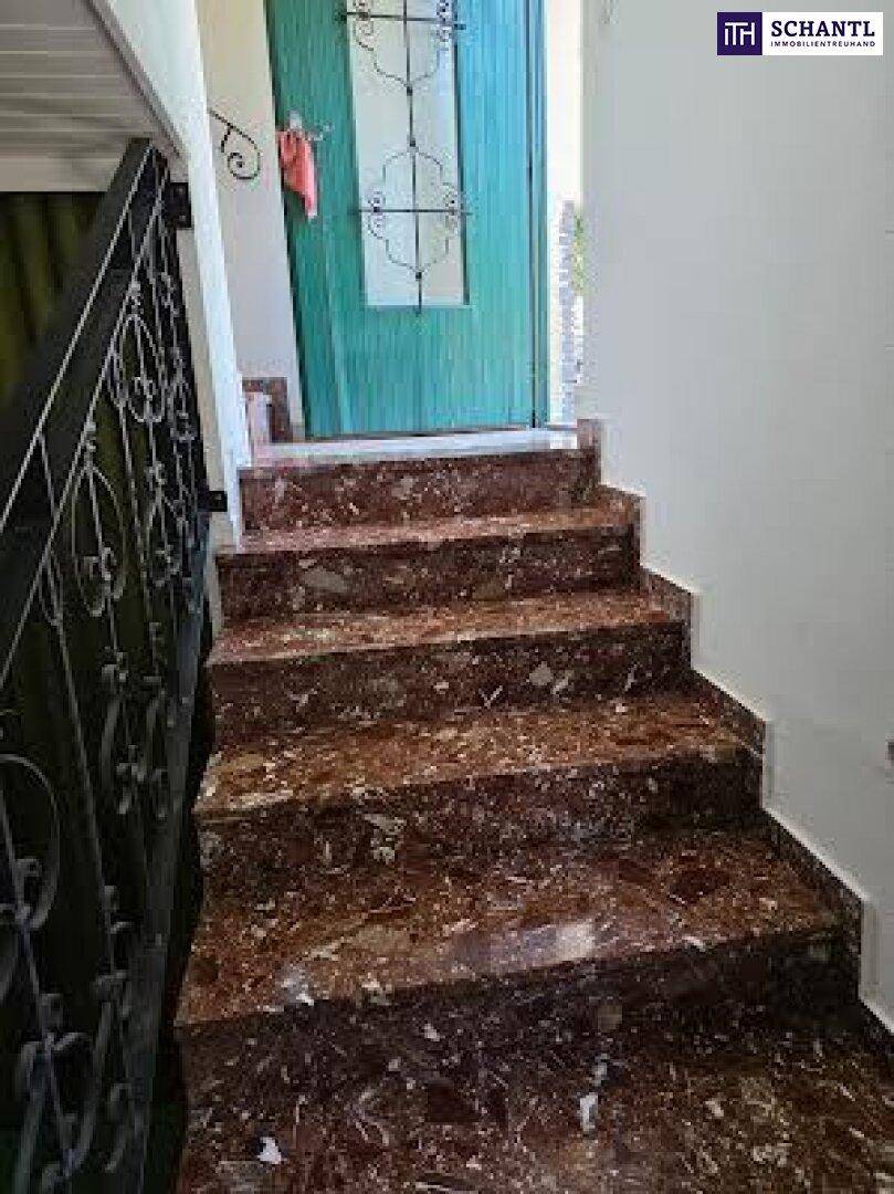 Marmortreppe führt zu einer grünen Tür mit dekorativem Glasfenster.