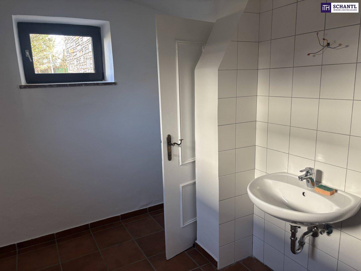 Kleines WC im Keller mit Waschbecken, Fliesen und Fenster.