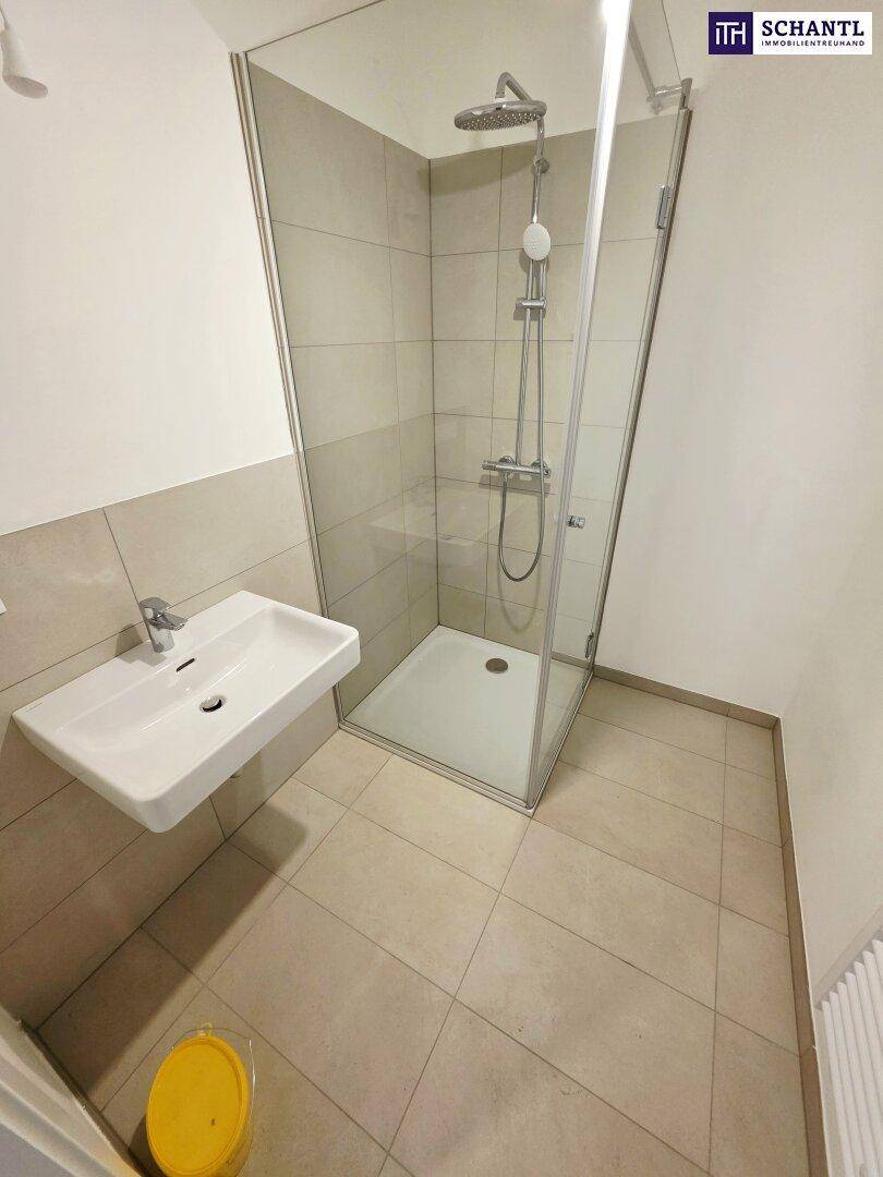 Modernes Badezimmer mit ebenerdiger Dusche, Waschbecken und hellen Fliesen.