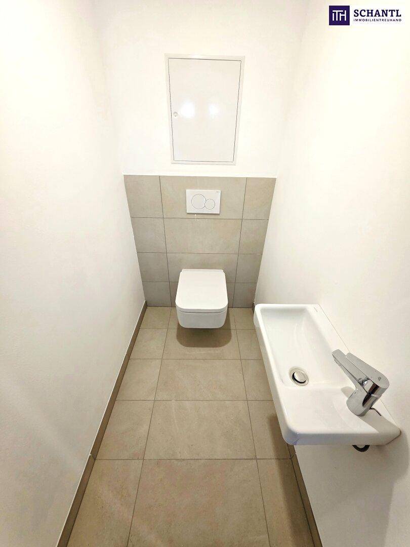 Modernes Gäste-WC mit wandhängender Toilette, kleinem Waschbecken und hellen Fliesen.