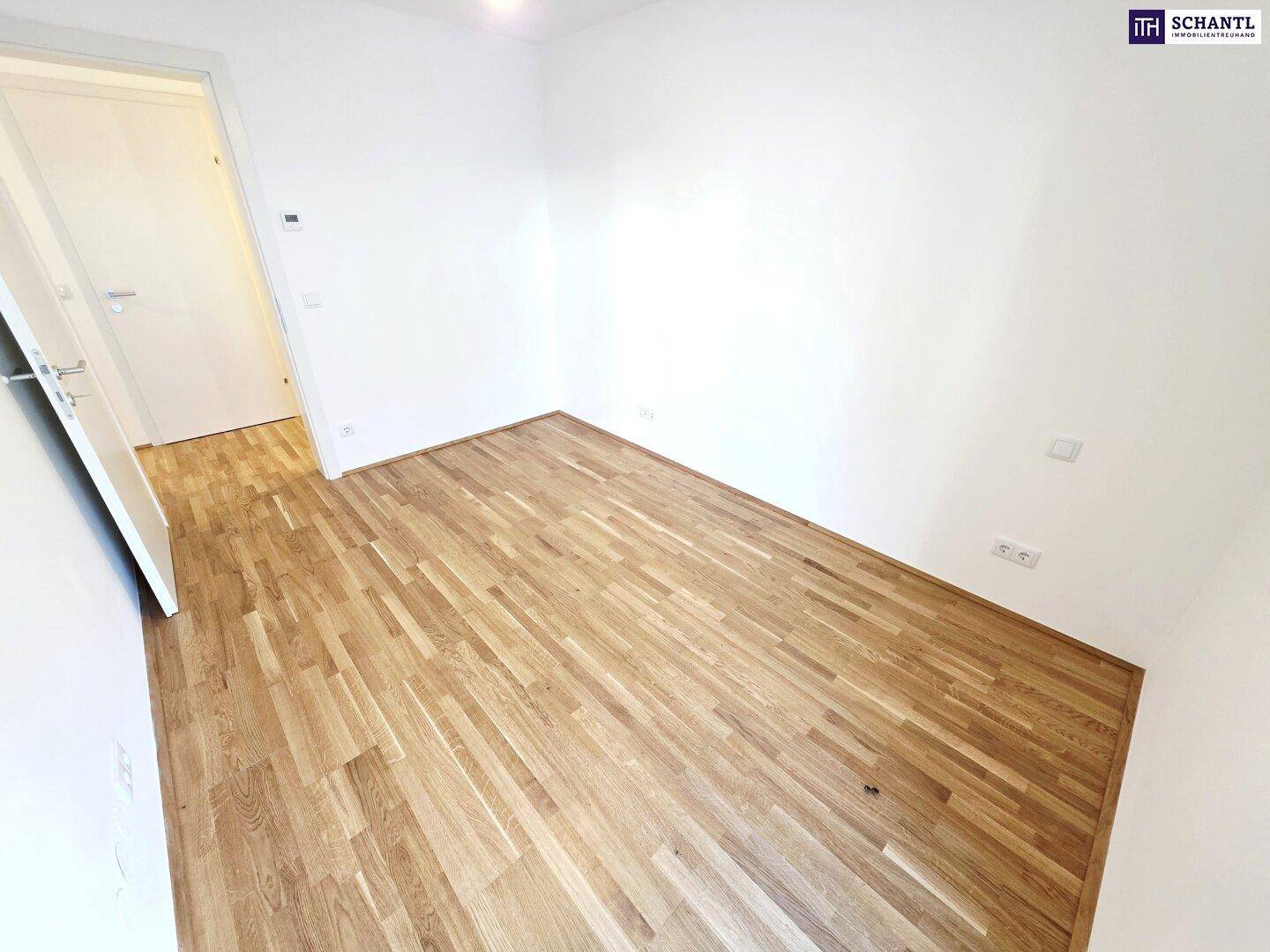 Helles Zimmer mit Parkettboden und weißen Wänden, bereit zur individuellen Einrichtung.
