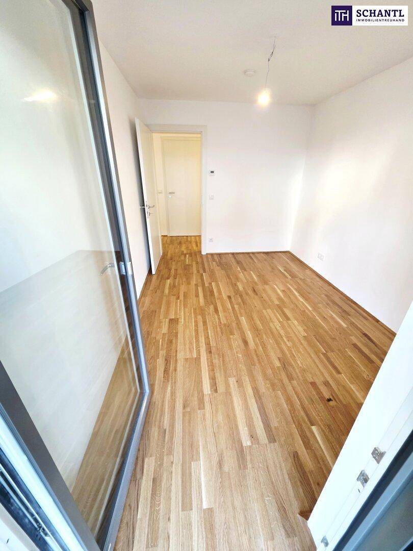Helles Zimmer mit Parkettboden und Zugang zum Außenbereich, ideal als Schlaf- oder Arbeitszimmer.